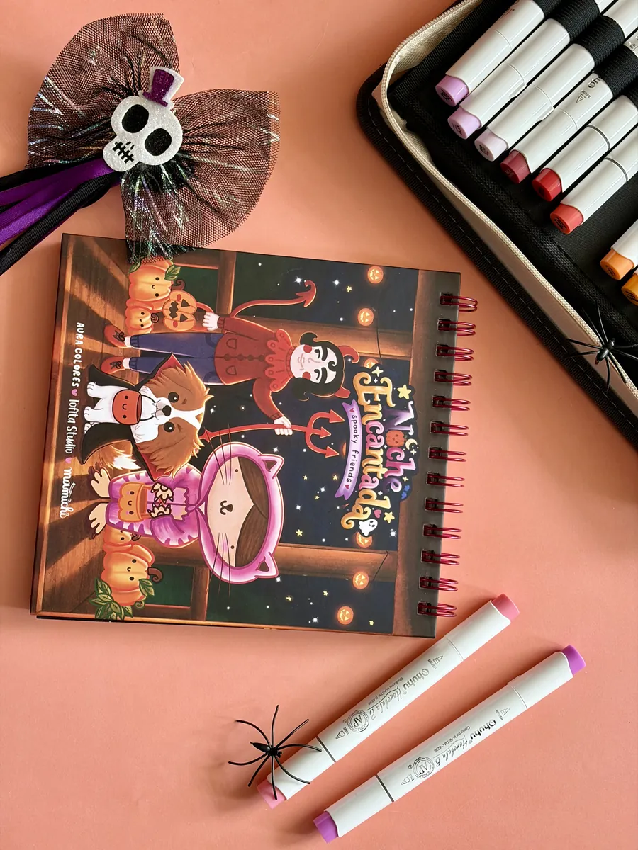Libro Noche Encantada sobre fondo durazno, con marcadores y detalles de Halloween